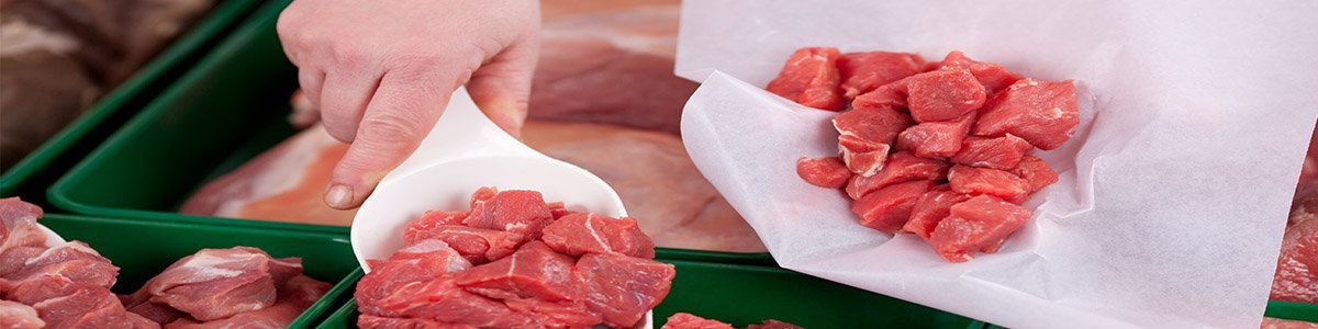 Diced meat being served from a butchers counter.