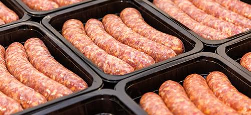 Sausages packed in black plastic meat trays.