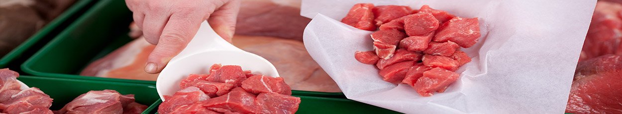 Diced meat being served from a butchers counter.